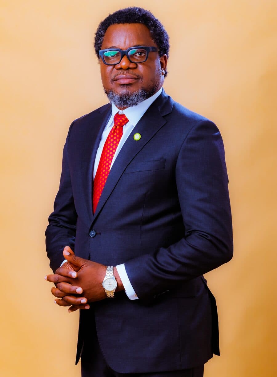 Dr. Michael Juwon Olarewaju in a navy suit and red tie, hands clasped